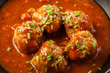 Meatballs with tomato sauce on black pan