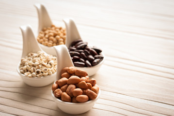 Different kinds of bean seeds, lentil, peas in dish on wooden ta