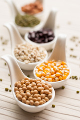 Different kinds of bean seeds, lentil, peas in dish on wooden ta