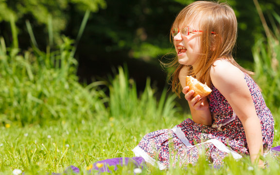 Funny playful little girl having picnic in park
