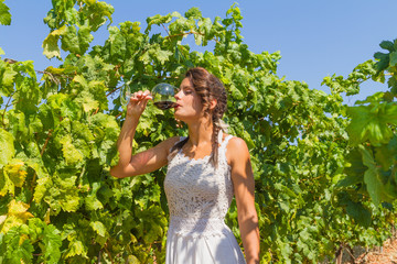 Young woman farmer tastes a glass of red wine.