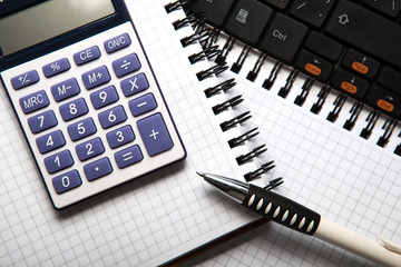 pen with calculator on a notebook and keyboard