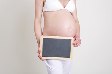 Pregnant woman with an empty blackboard