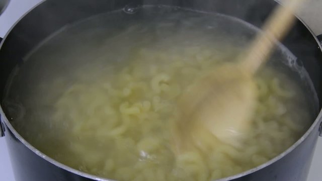 Stirring boiling noodles in a pan