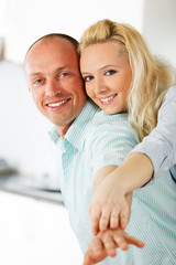 Piggyback couple enjoying in their kitchen