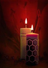 Two beeswax candles flame on a red background