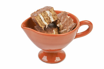 Pieces of chocolate sponge cake in a ceramic bowl isolated on wh