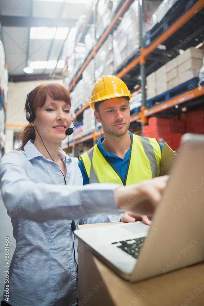 Wall mural smiling businesswoman wearing headset using laptop