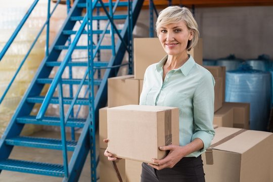 Smiling warehouse manager holding cardboard box