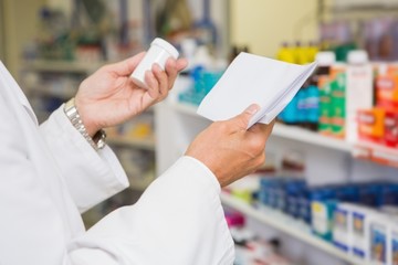 Pharmacist reading prescription and holding medicine - obrazy, fototapety, plakaty