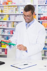Naklejka na ściany i meble Smiling pharmacist mixing a medicine