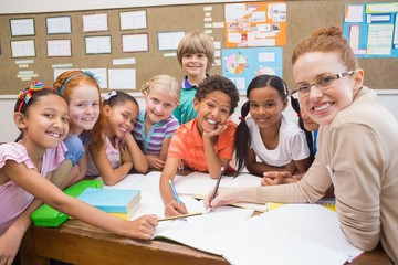 Teacher and pupils working at desk together