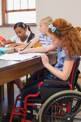 Cute pupils writing at desk in classroom