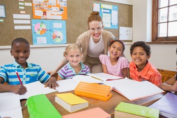 Pretty teacher helping pupils in classroom