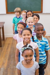 Cute pupils smiling at camera in classroom
