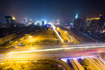 traffic light trails on overpass and cityscape at night