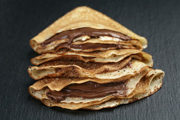 thin crepes or blinis with chocolate cream on slate board