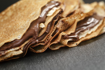 thin crepes or blinis with chocolate cream on slate board