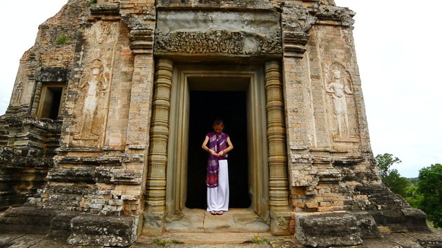 Zoom Out Female Buddhist Praying with Incense in Temple Doorway -   Angkor Wat Temple Cambodia