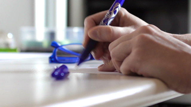 Woman hands taking a blue pen and writing a note it in a office