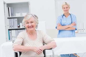 Obraz premium Senior patient sitting on wheelchair while nurse standing