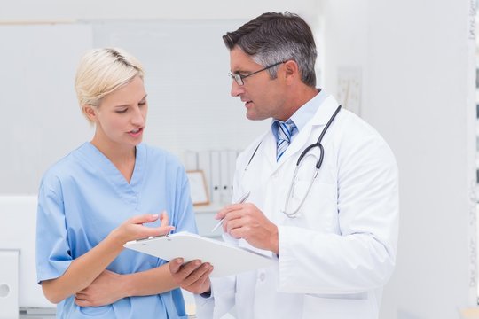 Doctor and nurse discussing over notes in clinic