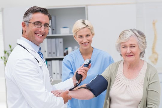 Doctor and nurse checking patients blood pressure