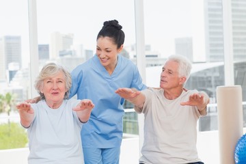 Trainer assisting senior couple to exercise