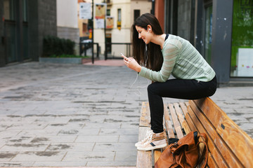 Young beautiful woman listening to music with phone in outdoors.