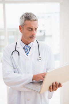 Doctor using laptop smiling to camera