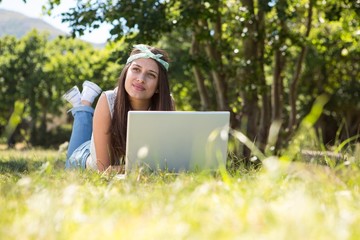 Pretty brunette using laptop in park