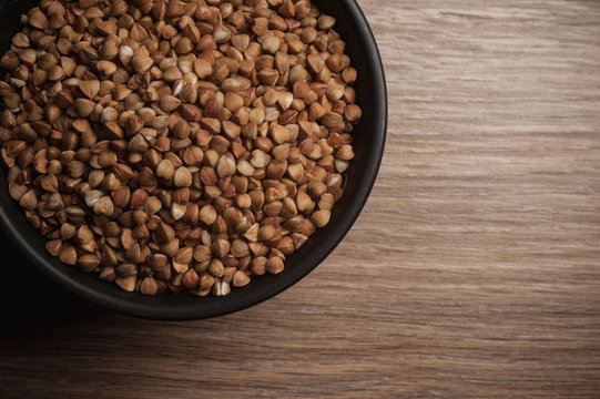 Buckwheat in bowl on wooden background. Closeup.
