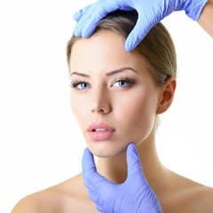 Beauty treatment of the young beautiful female face, doctor's ha