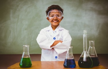 Cute boy with conical flasks in classroom