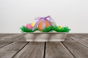 Ei mit einer Schleife als Geschenk in einem Osternest/Eierkarton