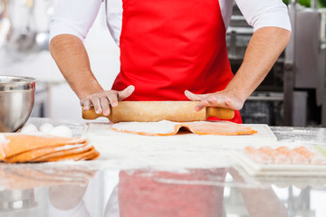 Midsection Of Chef Rolling Ravioli Pasta Sheet At Counter