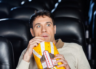 Obraz premium Frightened Man Watching Movie In Theater