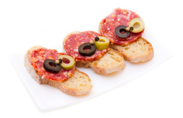 Bruschetta with salami and olives on white background