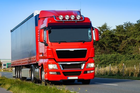 Roter Sattelschlepper unterwegs auf einer Landstra&szlig;e