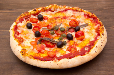 Pizza with anchovies and olives on wooden table