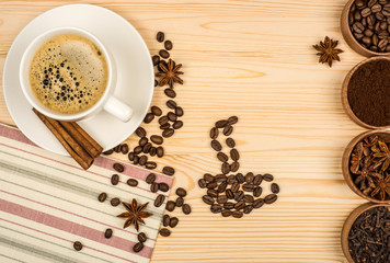 Coffee cup, anise stars, cinnamon sticks and coffee beans on woo