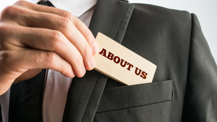 Businessman showing a wooden card reading - About us