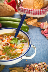 Vegetable soup in a metal bowl on a rural rustic wooden table.