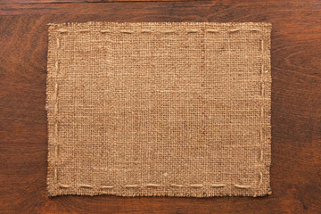 Frame of burlap, lies on a background of wood - obrazy, fototapety, plakaty