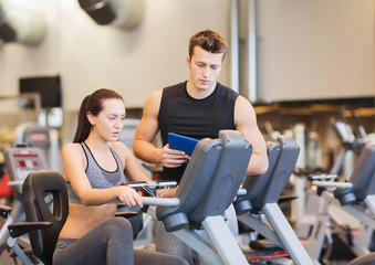 woman with trainer on exercise bike in gym