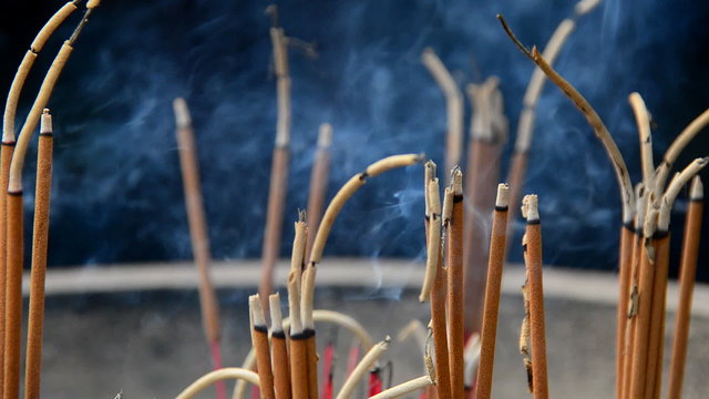 Close up of Incense Sticks Burning in Giant Pot in Front of Buddhist Temple 