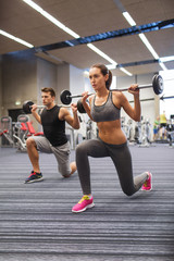 young man and woman training with barbell in gym