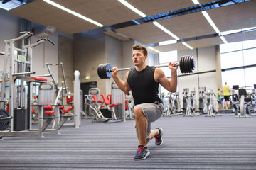 Obraz na płótnie Canvas young man flexing muscles with barbell in gym