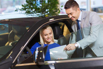 happy woman with car dealer in auto show or salon