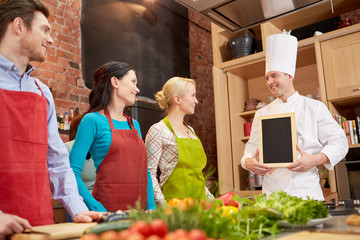 happy friends and chef cook with menu in kitchen